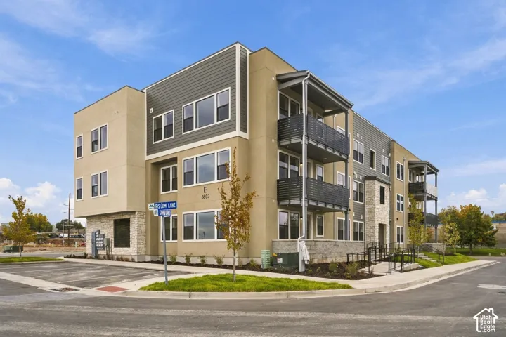 Multi-story building exterior featuring smooth stucco siding, horizontal lap siding, stone veneer accents, and private elevated balconies with metal railings