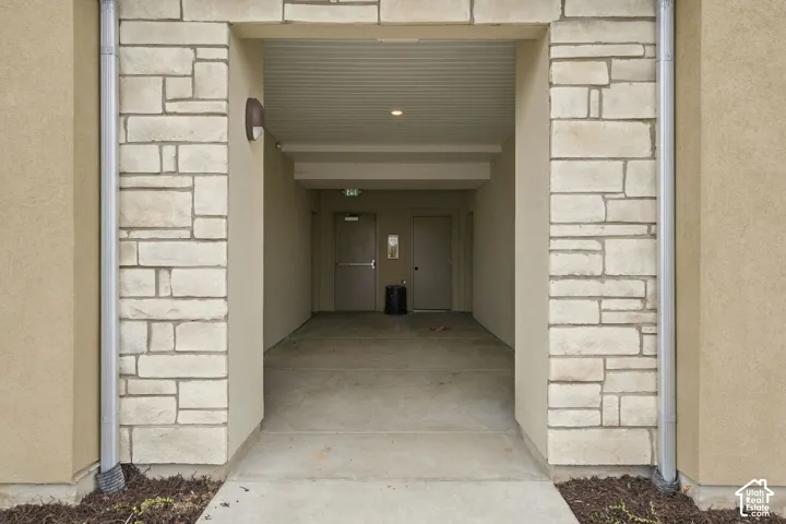 Exterior entry featuring stacked stone masonry, smooth stucco siding, recessed lighting, and dual metal doors