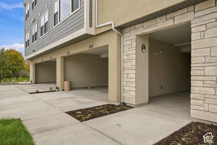Exterior featuring a mixed-material facade of stone veneer and horizontal siding, with dedicated covered carport parking bays and a concrete driveway