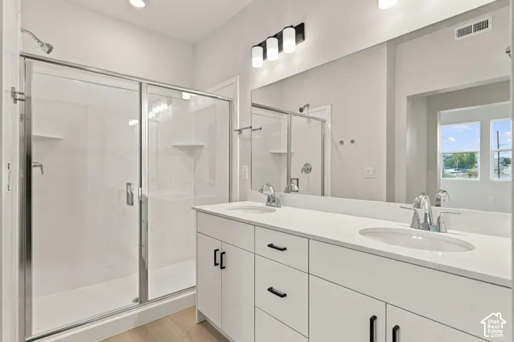Double vanity with integrated sinks, white cabinetry, quartz-style countertops, matte black hardware, and an expansive wall-mounted mirror