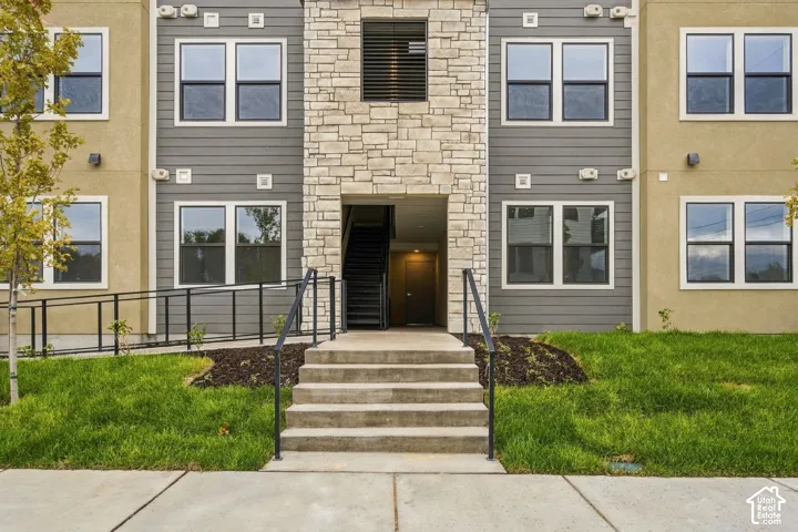 Multi-story exterior featuring stone veneer accents, horizontal siding, concrete entry steps with metal railings, and dual-pane windows
