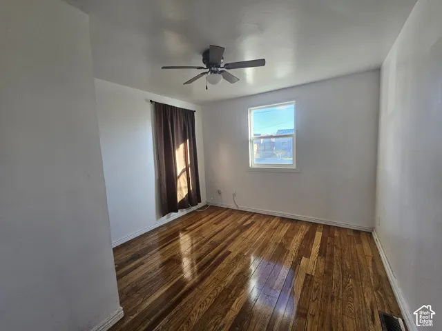 Wood-finish flooring, central ceiling fan with integrated lighting, and a single-pane window