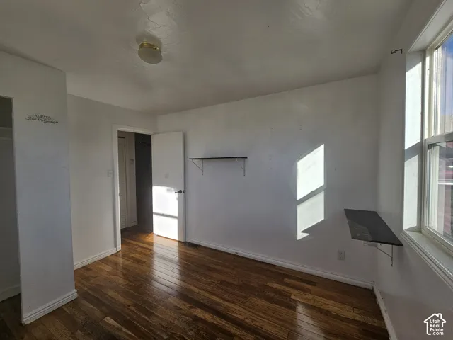 Interior space featuring wood-finish flooring, a flush-mount ceiling light fixture, a built-in wall-mounted shelf, and a built-in wall-mounted desk