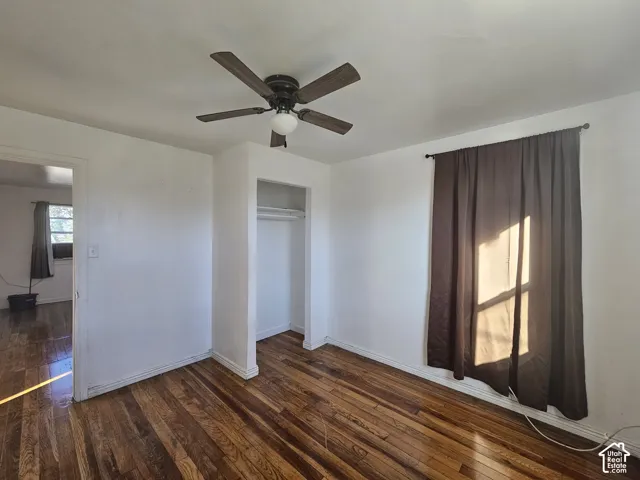 Room featuring wood-finish flooring, a ceiling fan with integrated lighting, and a built-in closet with shelving