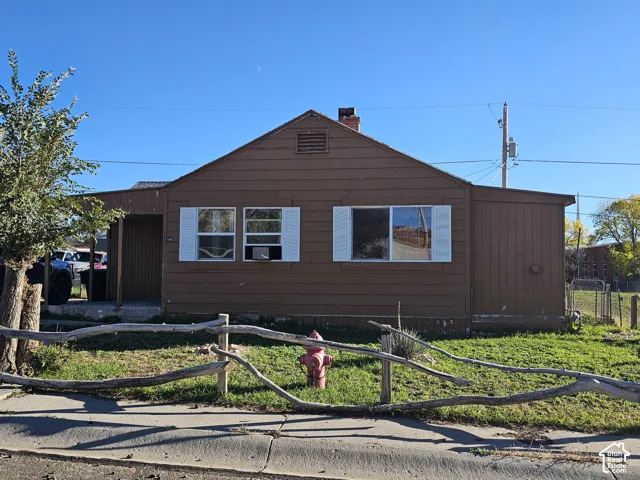 Single-story exterior with horizontal siding, white louvered shutters, covered porch, and chimney