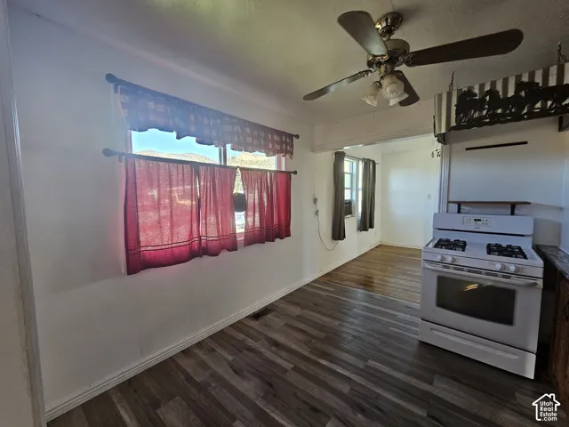 Wood-finish flooring, white freestanding gas range, and ceiling fan with multi-light fixture