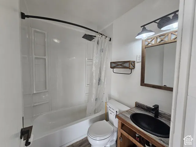 Bathroom featuring a vanity with a textured oval sink, matte black hardware, integrated molded shower surround with a curved shower rod, and dual-light industrial-style wall fixture