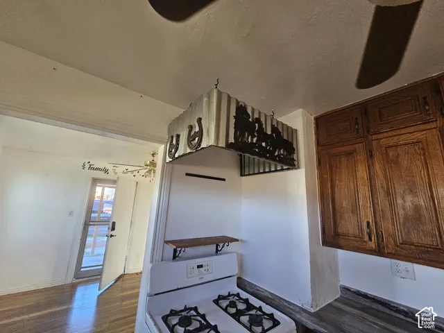 Custom metal range hood with decorative silhouette accents, stained wood cabinetry, and a white freestanding gas range