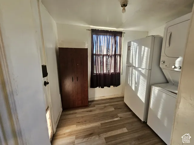Utility area featuring wood-finish flooring, a single-hung window, and a built-in vertical storage cabinet