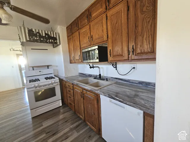 Kitchen featuring custom wood cabinetry, wood-finish flooring, dual-basin sink, and integrated microwave