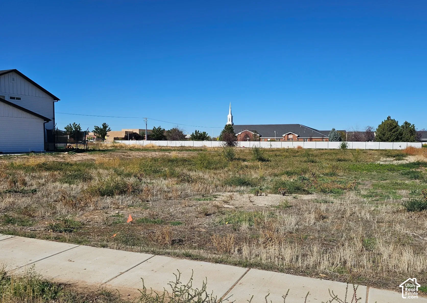 Open parcel of land featuring concrete sidewalk access and perimeter fencing
