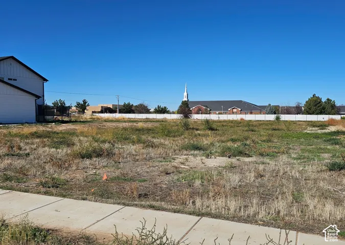 Open parcel of land featuring concrete sidewalk access and perimeter fencing