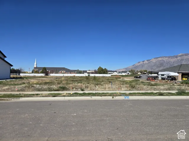 Cleared residential lot featuring paved street access, concrete curbing, and mountain scenery