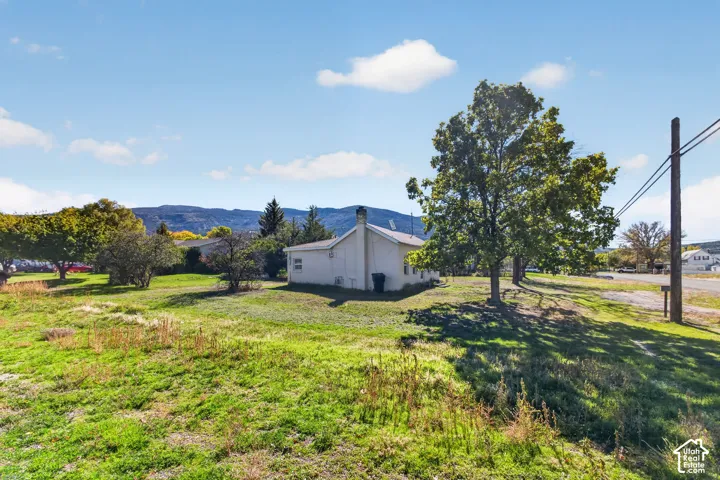 Exterior lot featuring mature trees, a masonry chimney, and mountain terrain backdrop