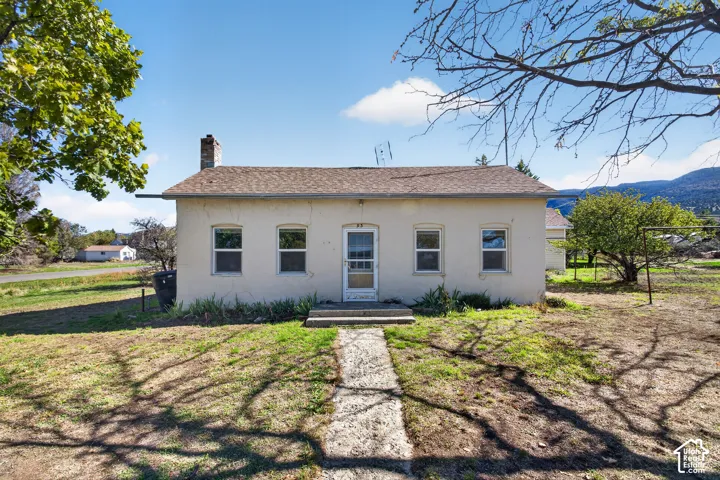 Stucco exterior featuring a pitched roof, exterior chimney, and arched window headers
