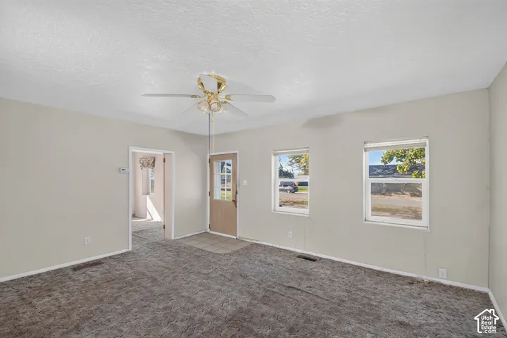 Neutral-toned interior space featuring a ceiling fan with multi-bulb light fixture, dual-pane windows, and a multi-panel entry door