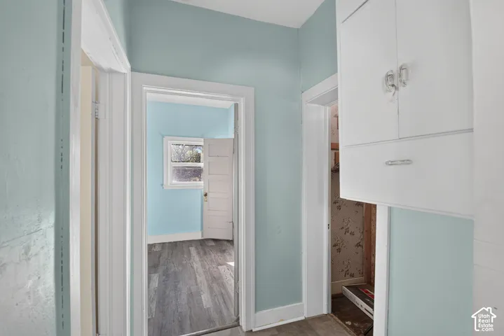 Hallway featuring built-in wall cabinetry, multi-panel doors, and wood-finish flooring