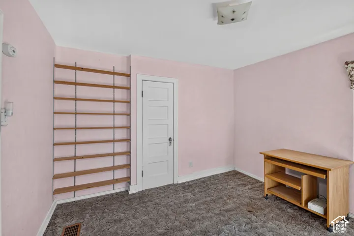 Room featuring wall-mounted adjustable shelving, a five-panel interior door with brushed metal hardware, and patterned carpeting