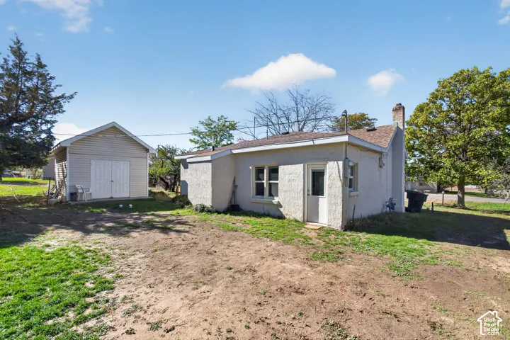 Stucco exterior featuring a masonry chimney and a detached storage structure with double doors