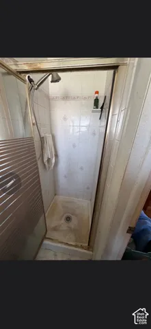 Shower stall featuring ceramic wall tile with decorative accents, a glass-panel door, and a handheld showerhead