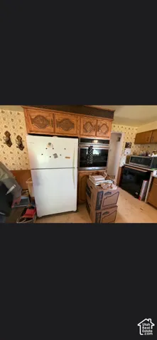 Kitchen featuring wood cabinetry with decorative detailing, a built-in wall oven, and a white refrigerator