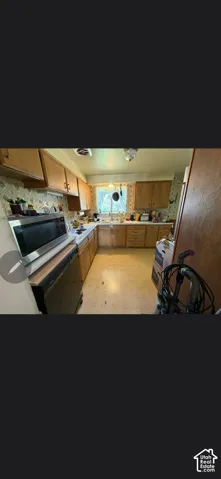 Kitchen featuring natural wood cabinetry, stainless steel over-the-range microwave, laminate countertops, and stainless steel sink with a faucet