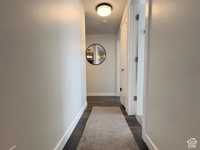 Hallway featuring wood-finish flooring, white door casings, and a flush-mount circular ceiling fixture