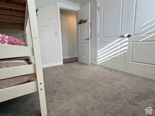 Room featuring neutral wall-to-wall carpeting, white interior doors with arched-panel detailing, and white door casing