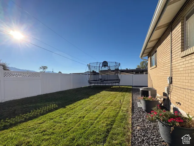 Exterior backyard featuring a brick facade, white privacy fencing with lattice detail, and a graveled side yard