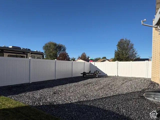 Low-maintenance side yard featuring a white vinyl privacy fence and crushed stone ground cover