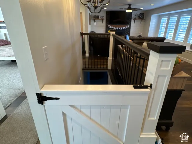 Custom white wooden stair gate with black iron hardware, ornate multi-light iron chandelier, dark metal stair railing, and wood-finish flooring