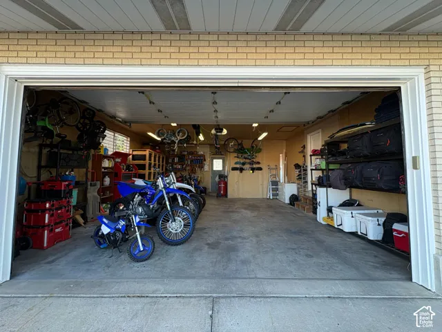 Multi-car garage featuring a concrete floor, light-colored brick exterior facade, and mounted overhead storage shelving