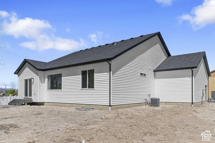 Single-story exterior featuring white horizontal siding, dark shingled roof, sliding glass patio door, and an installed central air conditioning unit