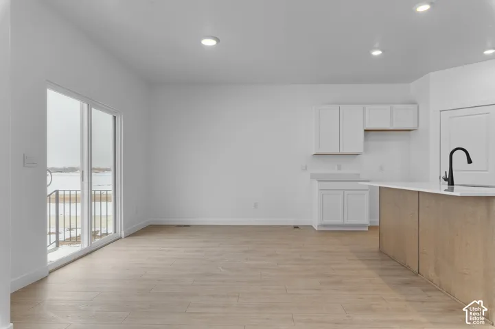 Kitchen featuring white cabinetry, wood-finish island, sliding glass patio door, recessed lighting, and wood-finish flooring