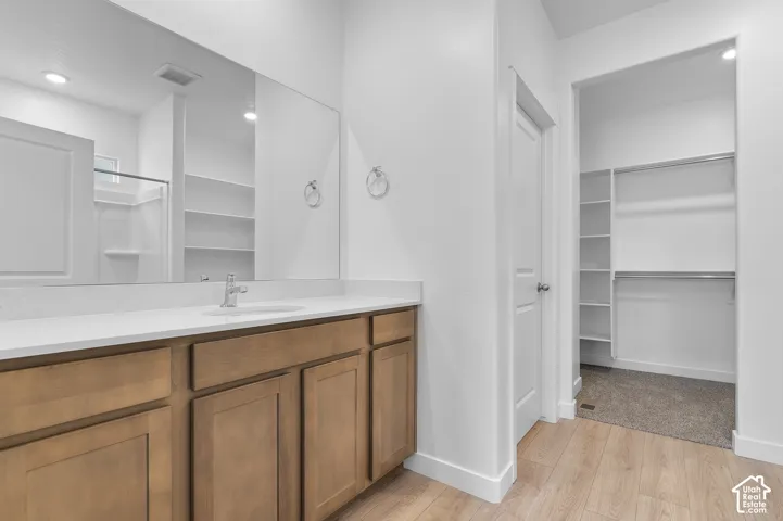 Bathroom vanity featuring wood-finish cabinetry, a stone-surface countertop, an integrated sink, and a large wall-mounted mirror