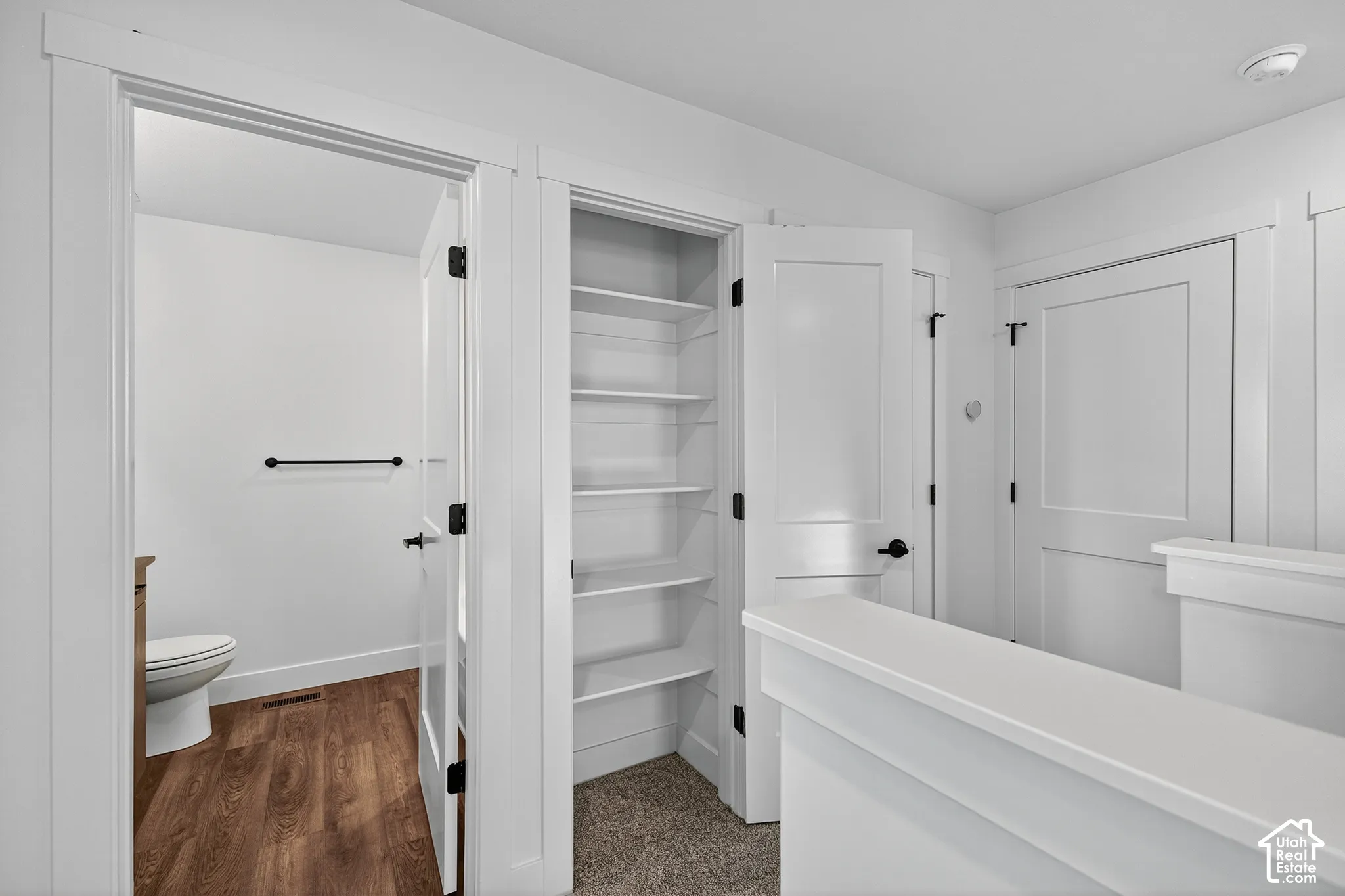 Built-in shelving unit with white finish, solid-core doors with matte black hardware, wood-finish flooring, and crisp white trim detailing
