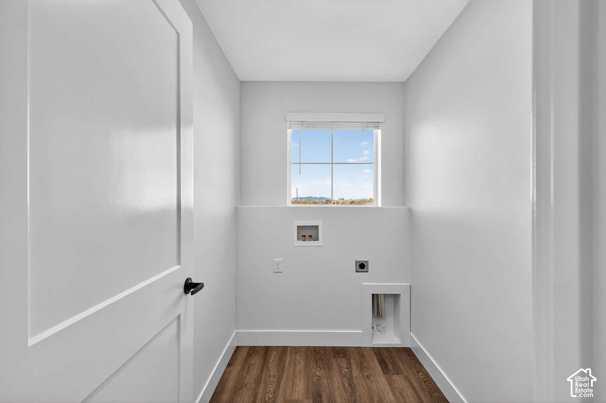 Laundry area featuring wood-finish flooring, a single-hung window with a blind, and dedicated washer and dryer hookups