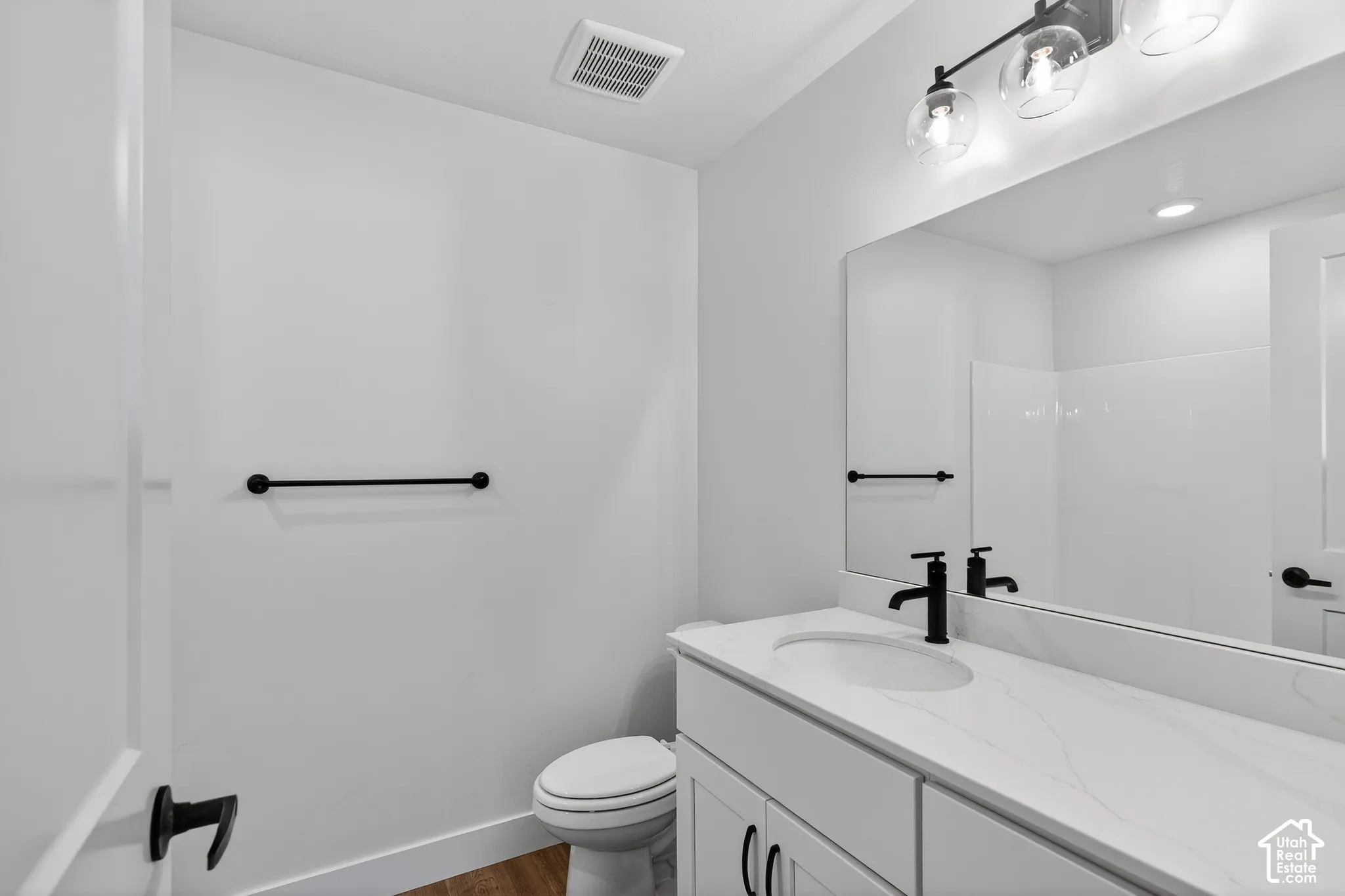 Vanity featuring a stone-composite countertop with integrated sink, white shaker-style cabinetry, matte black hardware, and an oversized wall-mounted mirror