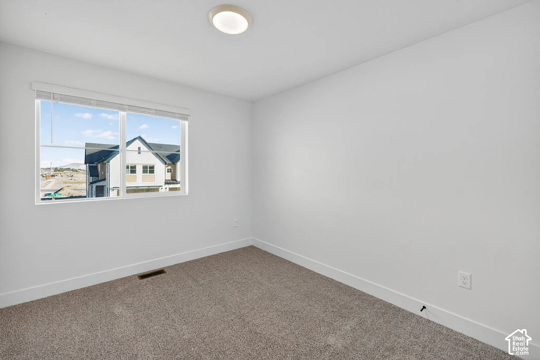 Neutral-toned carpeted flooring, white walls, and a window with horizontal blinds