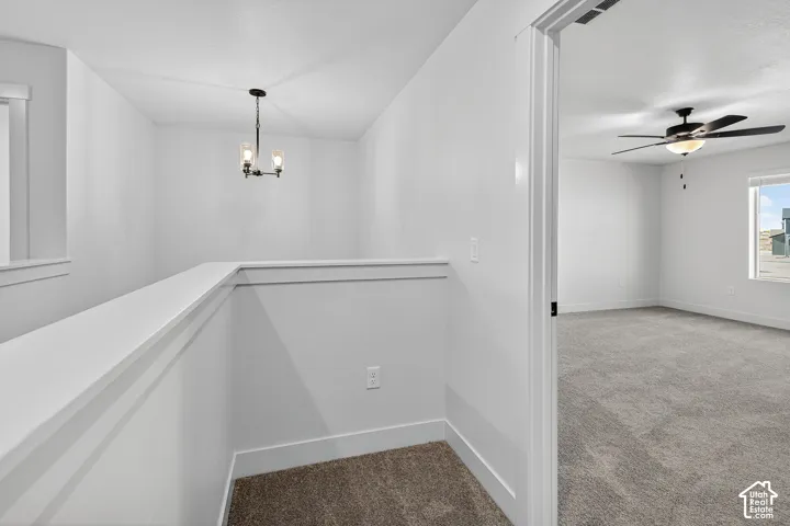 Open landing featuring a three-light pendant fixture, neutral wall-to-wall carpeting, and a ceiling fan with integrated lighting