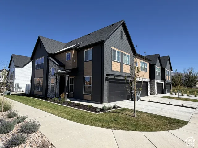 Multi-level exterior featuring dark horizontal siding, stone veneer accents, multi-pane windows, asphalt shingle roofing, and attached multi-car garages