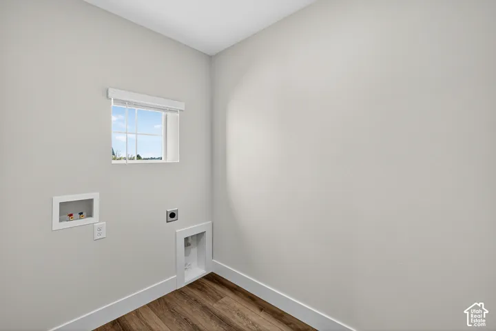 Neutral-toned walls, wood-finish flooring, a single-hung window with muntins, and built-in utility connections