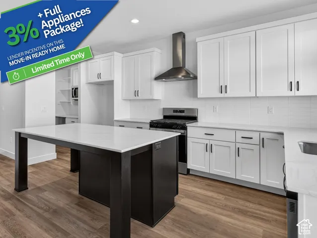 Kitchen featuring white shaker-style cabinetry, an expansive center island with a stone-finish countertop, stainless steel range hood, stone-finish perimeter countertops, and wood-finish flooring