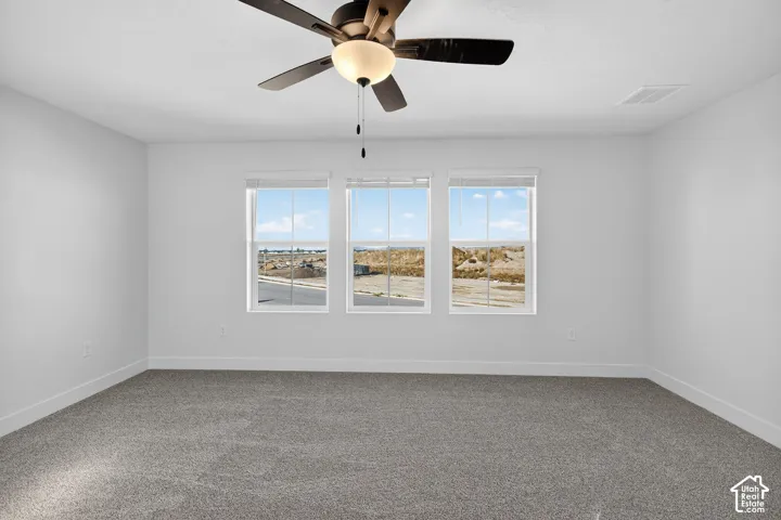 Room featuring wall-to-wall carpeting, three windows with blinds, and a central ceiling fan with an integrated light fixture