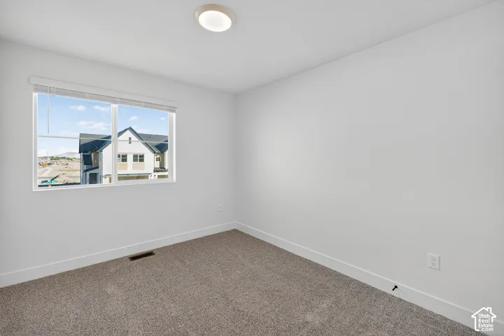 Neutral-toned carpeted flooring, white walls, and a window with horizontal blinds