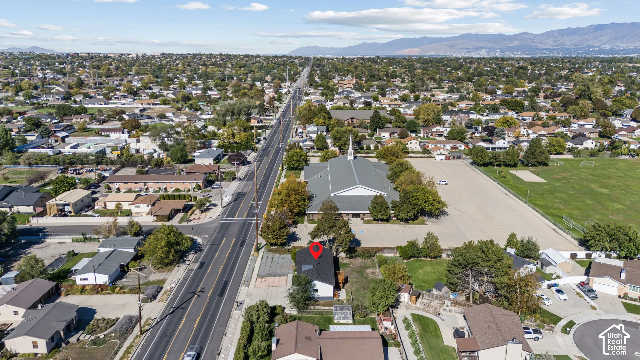 Aerial perspective of a detached residential structure featuring a dark-toned pitched roof, integrated skylights, and proximity to regional mountain ranges