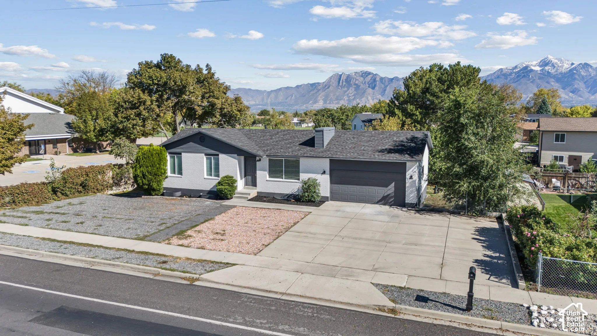 Single-level exterior featuring painted brick siding, an attached garage, and a mountain backdrop