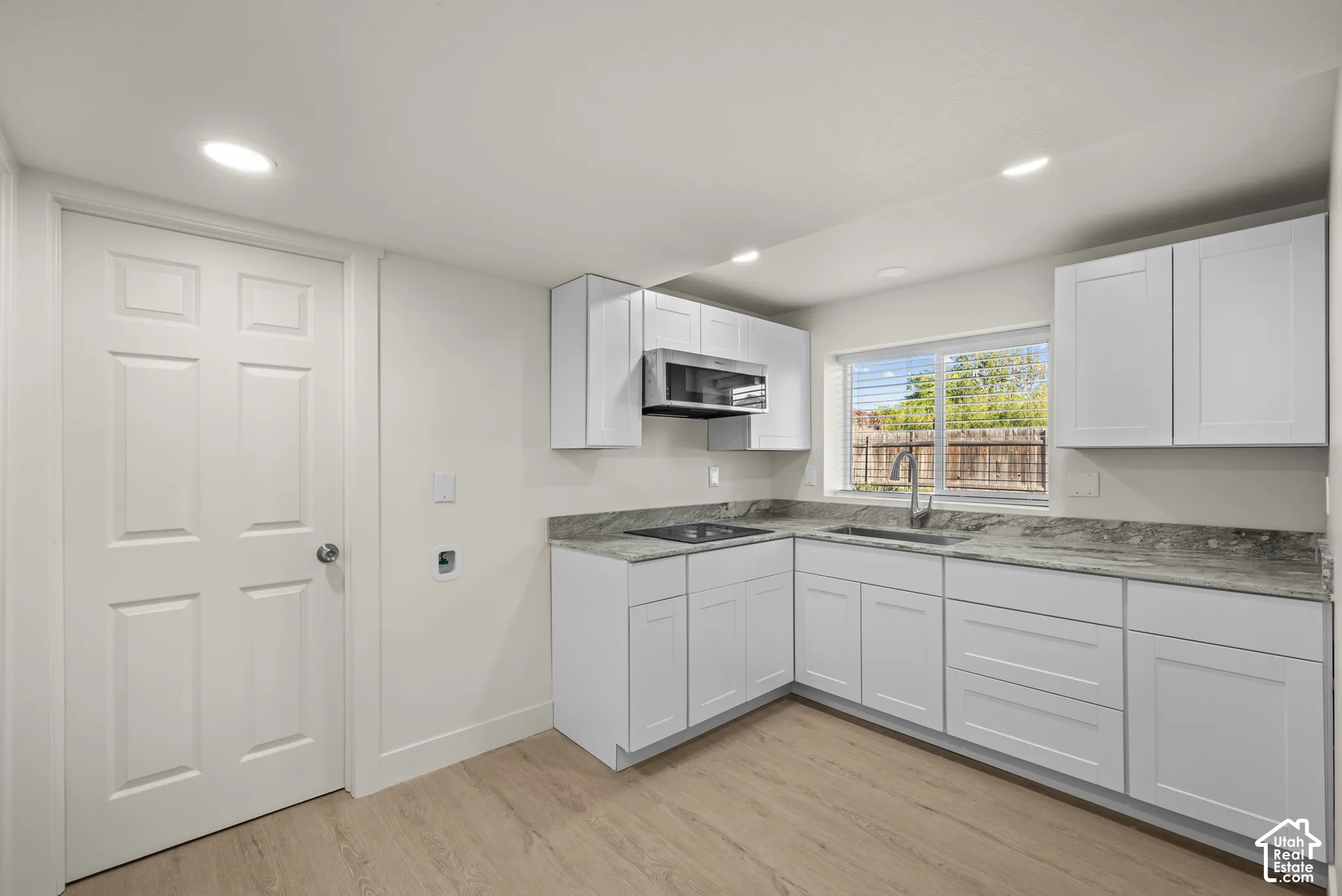 Kitchen featuring white shaker-style cabinetry, stone-finish countertops, recessed lighting, wood-finish flooring, and a built-in microwave