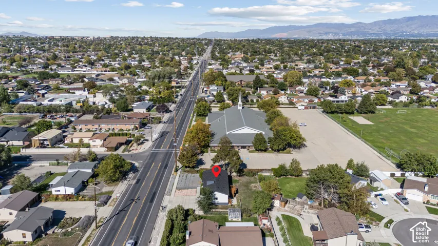Aerial perspective of a detached residential structure featuring a dark-toned pitched roof, integrated skylights, and proximity to regional mountain ranges