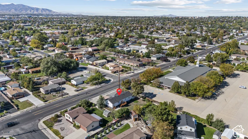Aerial view featuring a single-story residence with a dark shingle roof and a spacious backyard